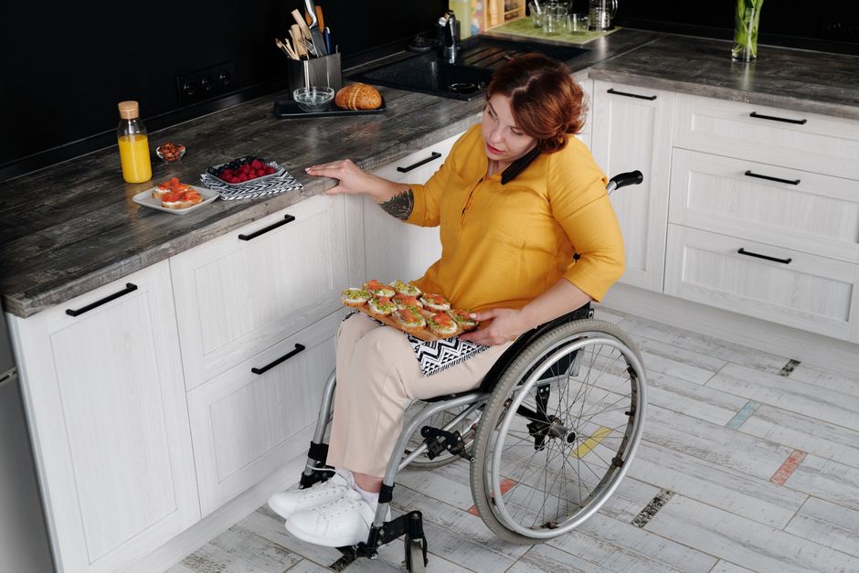 Woman using wheelchair prepares breakfast in kitchen, showing inclusivity.